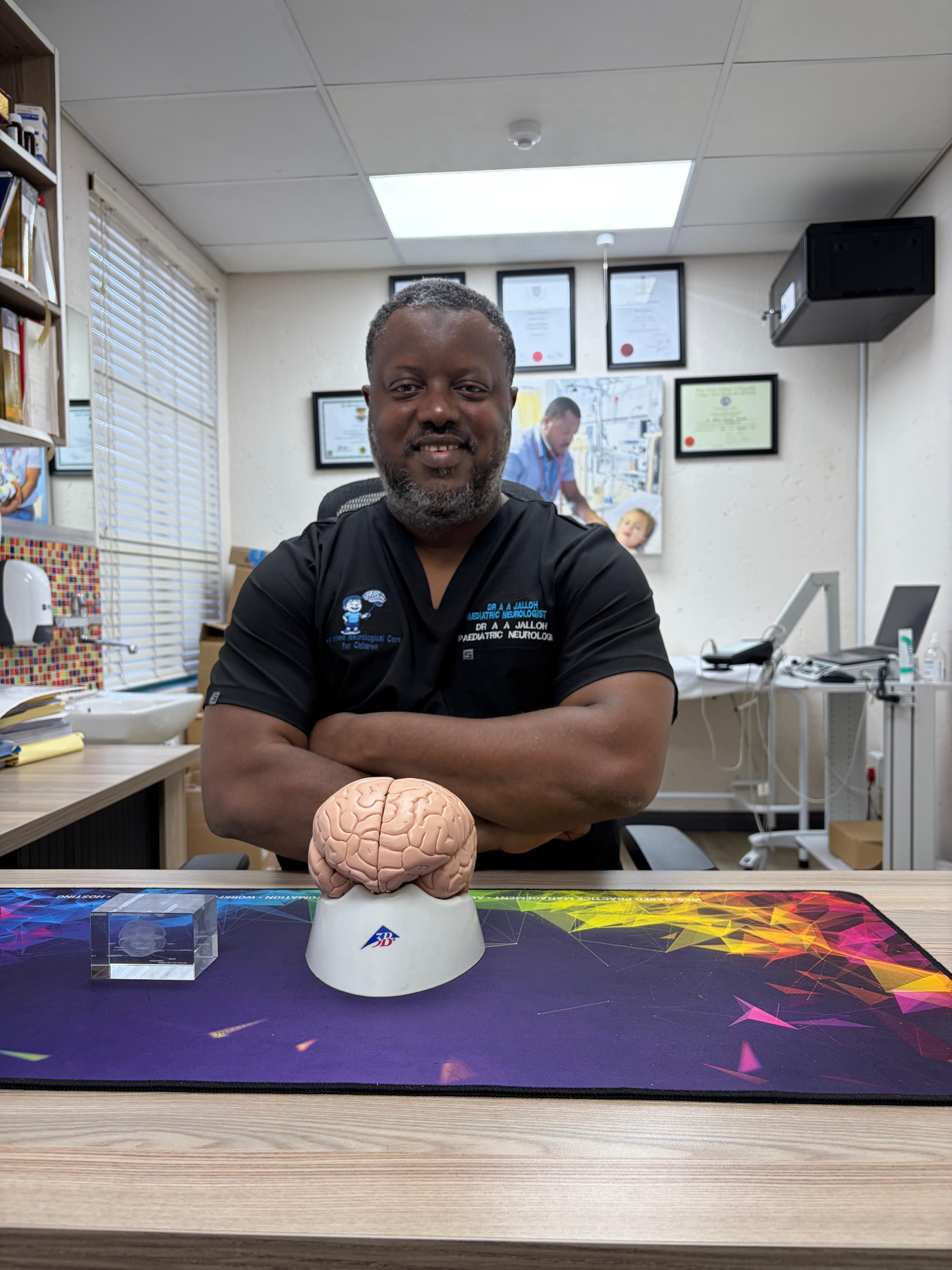 Dr A A Jalloh in the consultation room with a brain model